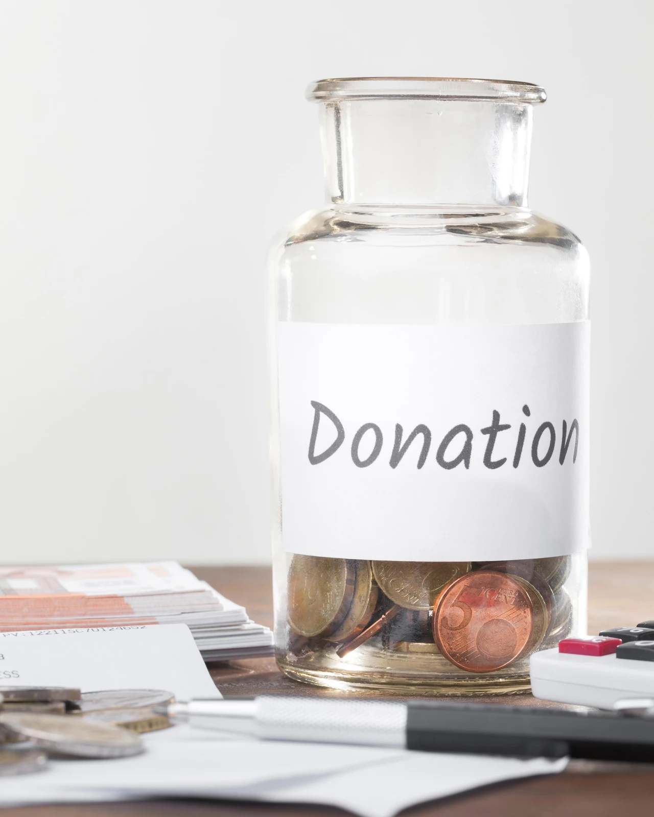 Glass donation jar with coins for a monthly giving program