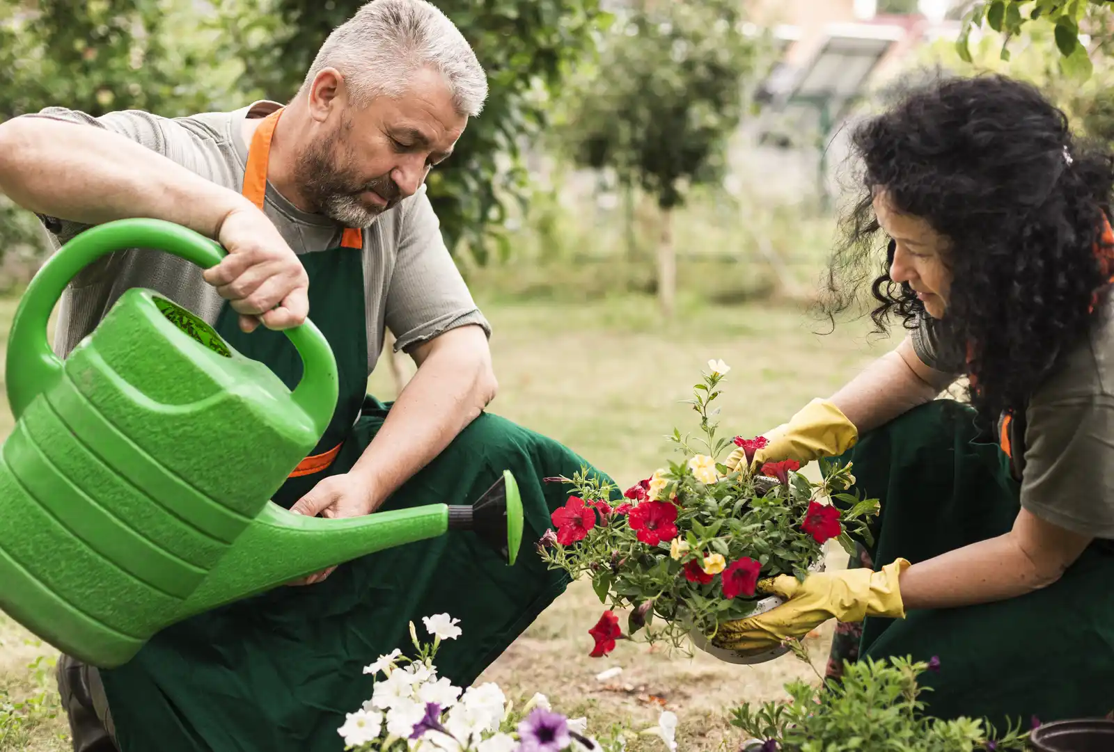 Volunteers watering and planting flowers in a community garden